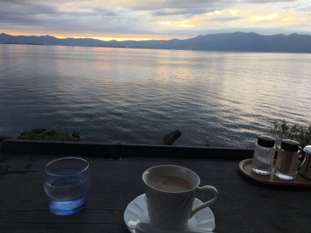 滋賀県・琵琶湖畔にある「シャーレ水ヶ浜」。夕暮れ時に訪れ、湖面に映る光を眺めながらコーヒーを飲む。何もしない時間の贅沢さを思い出させてくれる湖畔喫茶を訪ねた。